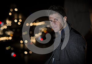 Attractive young man portrait at night with city lights behind him