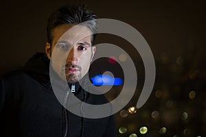 Attractive young man portrait at night with city lights behind him