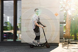 Attractive Young Man Riding Modern Kick Scooter At City. Conception Of Fast Transportation Without Traffic Jam