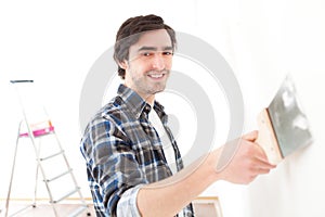 Attractive young man scrubing a wall in his flat