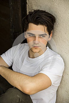 Attractive young man sitting on old door's threshold