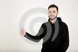 Attractive young man with a small beard in black clothes stands