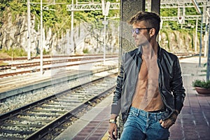 Attractive young man standing by railroad tracks