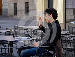 Atraktívne mladý muž štúdium alebo pracovné v káva obchod prenosný počítač v mesto vonku 