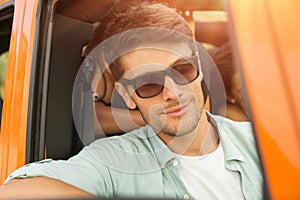 Attractive young man in sunglasses sitting on a front seat