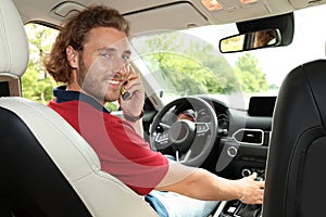 Attractive young man talking on phone while driving car