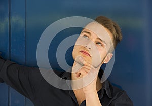 Attractive young man thinking, looking up with hand on his chin