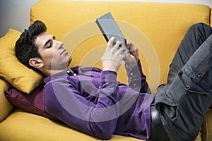 Attractive young man using tablet PC while laying