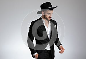 Attractive young man walking in black tuxedo on grey background