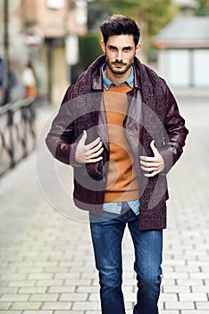 Attractive young man walking in an urban road in winter clothes.