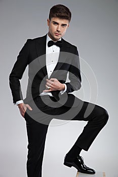 Attractive young man wearing a black tuxedo posing relaxed