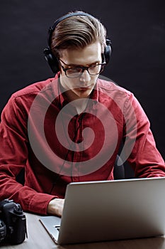 Attractive young man wearing headphones and typing in the laptop