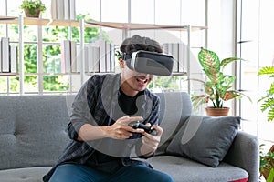 Attractive young man wearing virtual reality headset or 3d glasses sitting on sofa at home