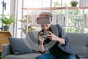 Attractive young man wearing virtual reality headset or 3d glasses sitting on sofa at home
