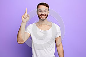 Attractive young man in whilte t-shirt pointing up his finger