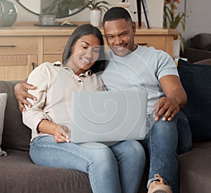 Attractive young mixed race couple relaxing on the sofa and using a laptop. Smiling African American couple watching