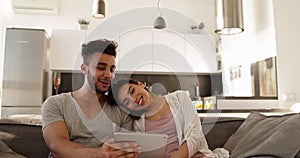 Attractive Young Mixed Race Couple Using Tablet Computer, Happy Hispanic Man Asian Woman Together Sitting On Coach