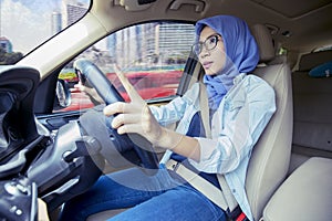 Attractive young muslim woman driving car