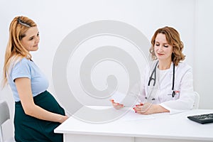 Attractive young pregnant woman with blonde hair came to doctor with folder of paper documents.
