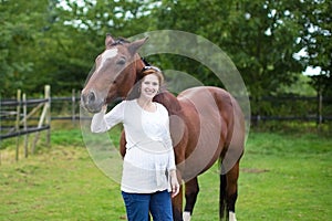 Attractive young pregnant woman and horse in field