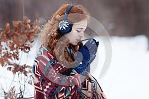 Attractive young red-haired woman drinking a hot drink from a mug