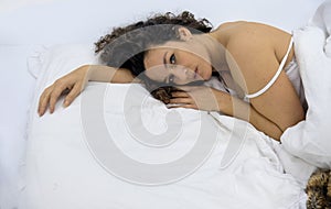 attractive, young, sexy, sensual seductive longing brunette woman, curly brown hair lying in bed in white nightwear at sunday