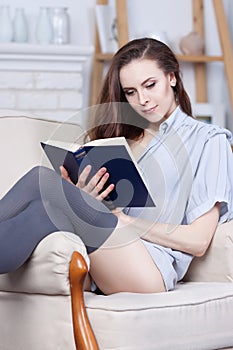 Attractive young slim brunette is reading a book