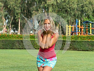 Attractive young smiling beautiful curly blonde hair slim girl fashion portrait in pink T-shirt posing looking away calm look, in