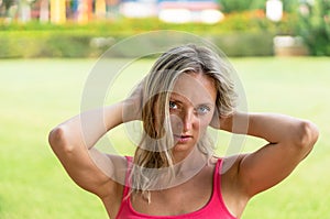 Attractive young smiling beautiful curly blonde hair slim girl fashion portrait in pink T-shirt posing looking away calm look, in