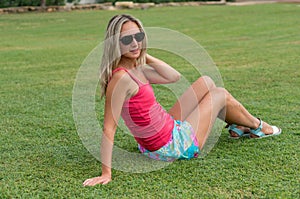 Attractive young smiling beautiful curly blonde hair slim girl fashion portrait in pink T-shirt posing looking away calm look, in