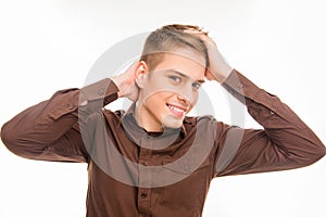 Attractive young smiling man in brown shirt touhing his hair photo