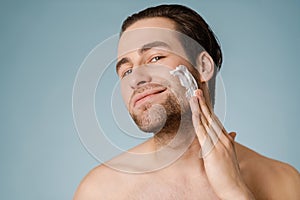 Attractive young smiling nude man with shaving foam