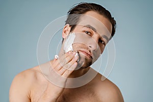 Attractive young smiling nude man with shaving foam