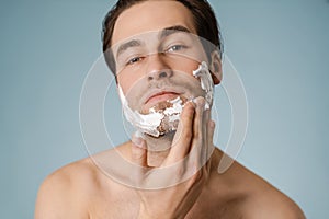 Attractive young smiling nude man with shaving foam