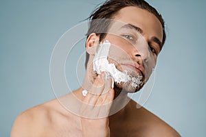 Attractive young smiling nude man with shaving foam