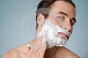 Attractive young smiling nude man with shaving foam