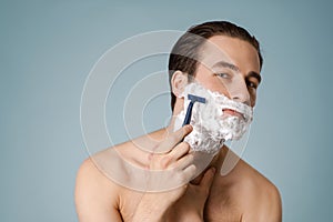 Attractive young smiling nude man with shaving foam