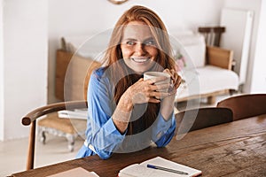 Attractive young smiling woman having cup of coffee