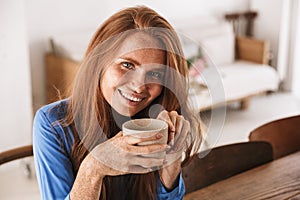 Attractive young smiling woman having cup of coffee