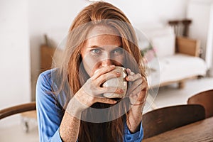 Attractive young smiling woman having cup of coffee