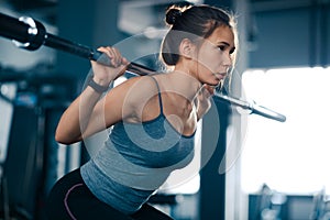 Attractive Young Sports Woman Doing Squats with Barbell in the Gym. Fitness and Healthy Lifestyle.