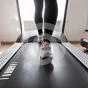 Attractive young sporty woman working out in the gym. Girl is doing cardio training on treadmill. Walking on a treadmill.