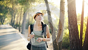 Attractive young tourist girl refreshing by drinking water after backpacker journey