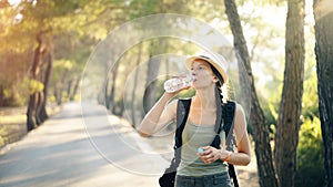 Attractive young tourist girl refreshing by drinking water after backpacker journey
