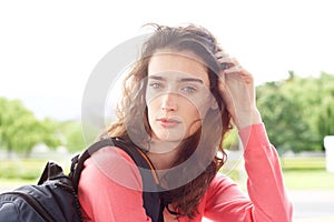 Attractive young traveler woman with hand in hair and backpack