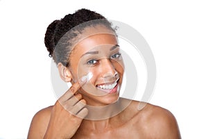 Attractive young woman applying cream on face