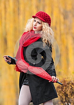 Attractive young woman in a autumn fashion shoot. Beautiful fashionable young girl with red accessories outdoor