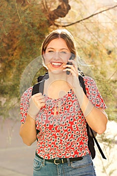 Attractive young woman with backpack talking on mobile phone