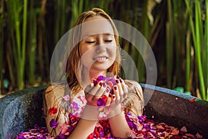 Attractive Young woman in bath with petals of tropical flowers and aroma oils. Spa treatments for skin rejuvenation