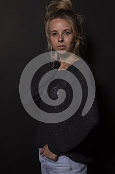 Attractive young woman with blond bunched hair posing on black background